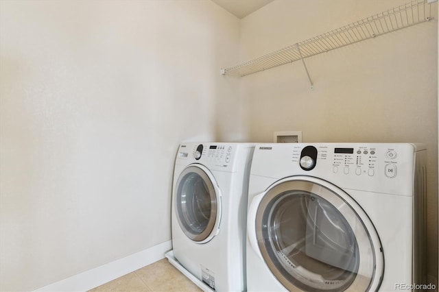 clothes washing area with washing machine and clothes dryer and light tile patterned floors