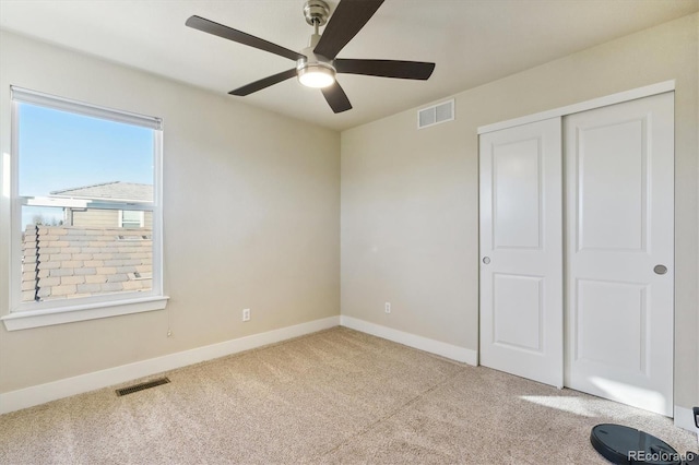 unfurnished bedroom featuring ceiling fan, light carpet, and a closet