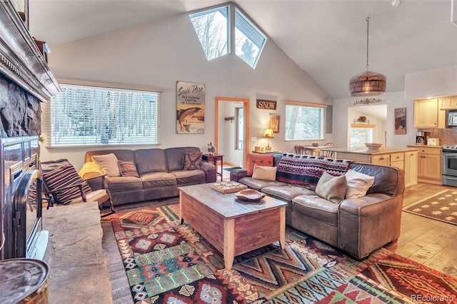 living room with high vaulted ceiling, a fireplace, and light wood-type flooring