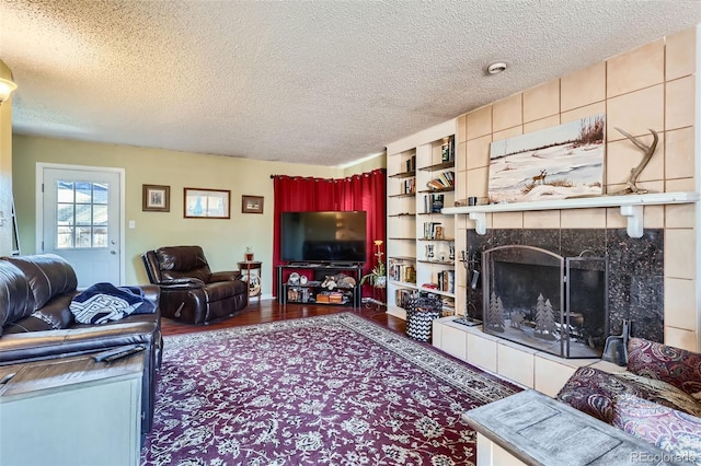 living room with a tile fireplace, hardwood / wood-style floors, and a textured ceiling