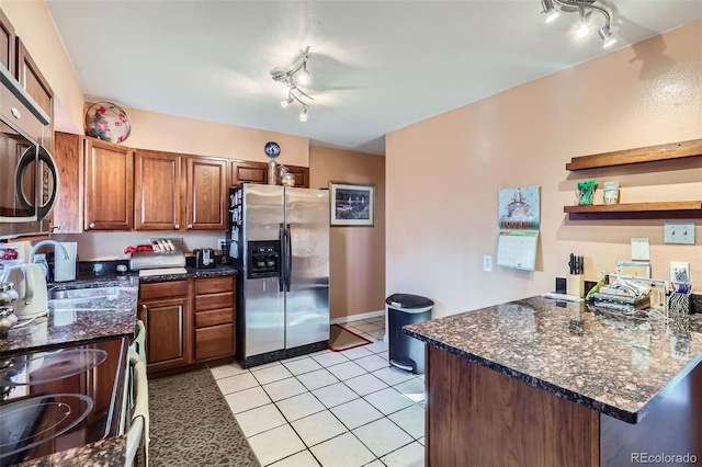 kitchen featuring sink, kitchen peninsula, dark stone countertops, light tile patterned flooring, and appliances with stainless steel finishes