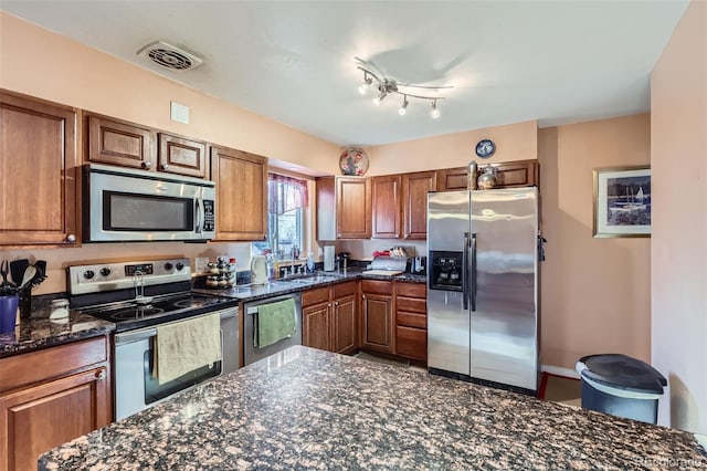 kitchen with sink, appliances with stainless steel finishes, and dark stone counters