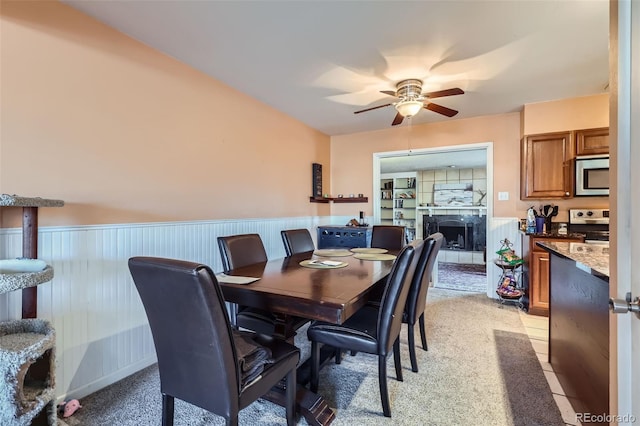 dining area with ceiling fan and a tiled fireplace