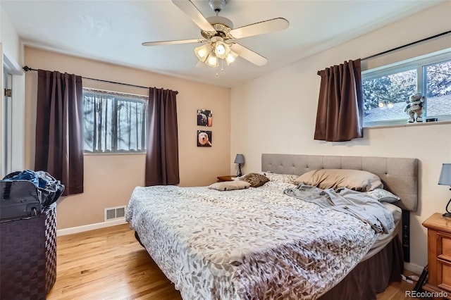 bedroom with light wood-type flooring, multiple windows, and ceiling fan