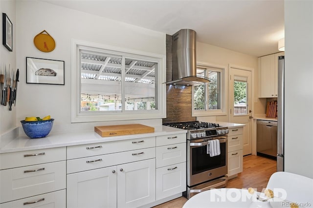 2965 S Gilpin St, Denver, CO 80210 - kitchen with range hood, stainless steel appliances, light countertops, light wood-style floors, and white cabinetry
