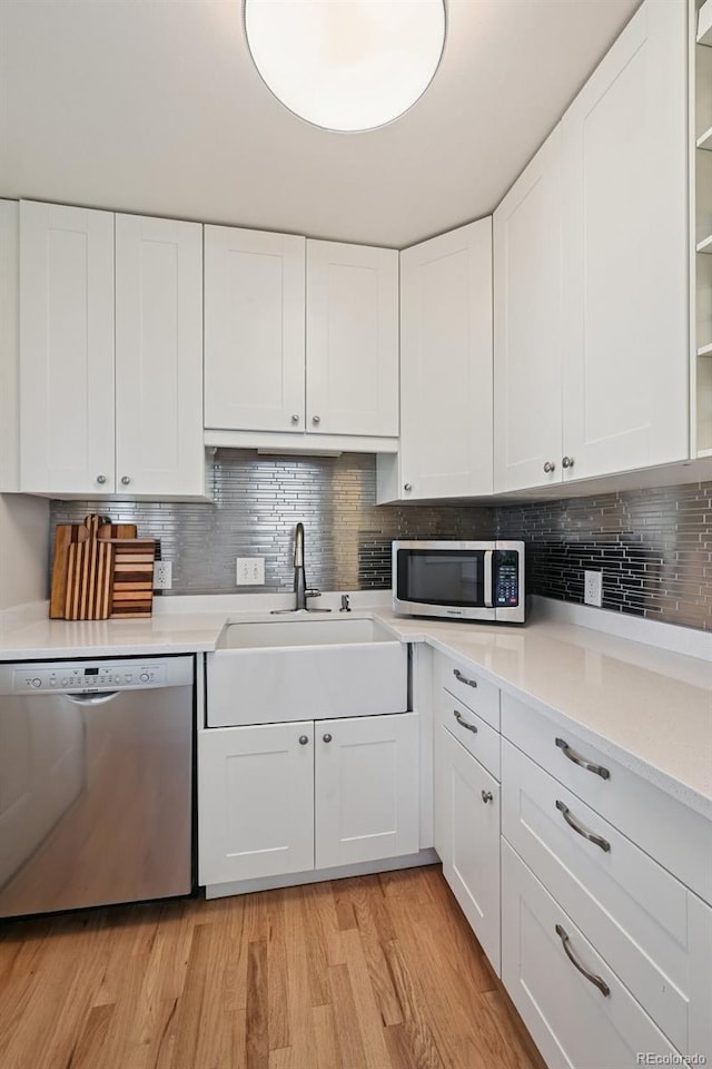 2965 S Gilpin St, Denver, CO 80210 - kitchen featuring appliances with stainless steel finishes, light wood-style floors, light countertops, white cabinets, and backsplash
