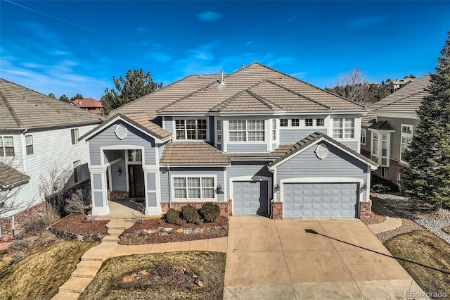 view of front of house featuring brick siding, driveway, a tile roof, and an attached garage