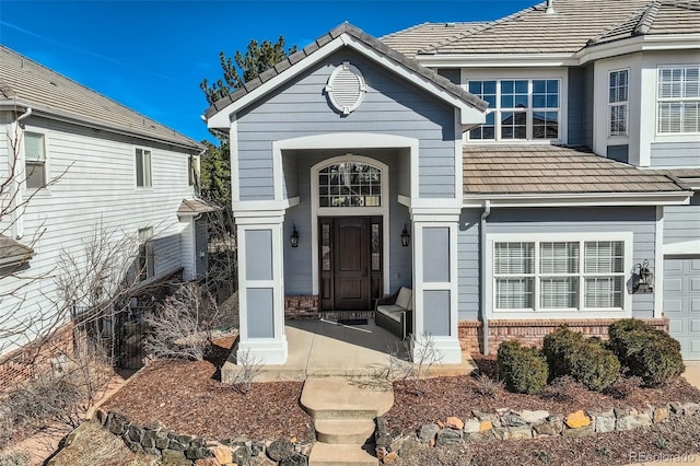 entrance to property featuring a tile roof and brick siding