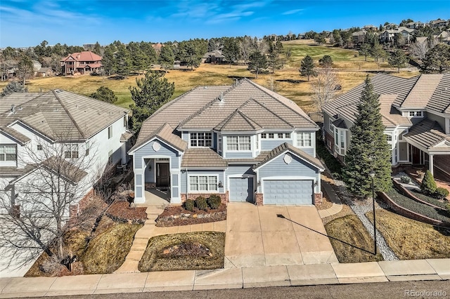 view of front of home featuring a tiled roof, a residential view, a garage, and driveway