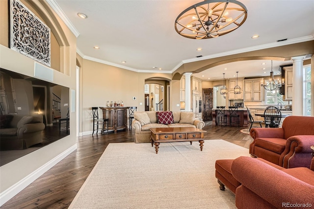 living room featuring decorative columns, arched walkways, an inviting chandelier, and dark wood-style flooring