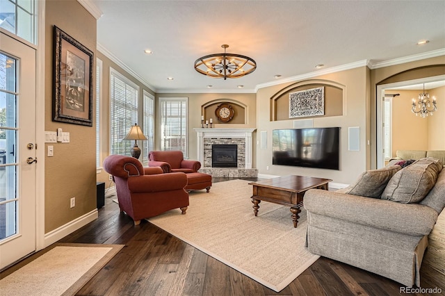 living area with crown molding, baseboards, dark wood finished floors, a fireplace, and an inviting chandelier