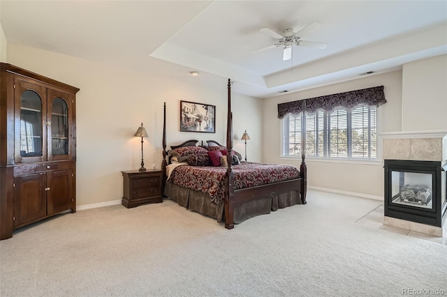 bedroom with visible vents, light colored carpet, a raised ceiling, and baseboards