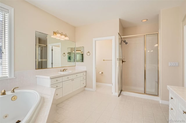 bathroom featuring vanity, a tub with jets, a stall shower, and baseboards