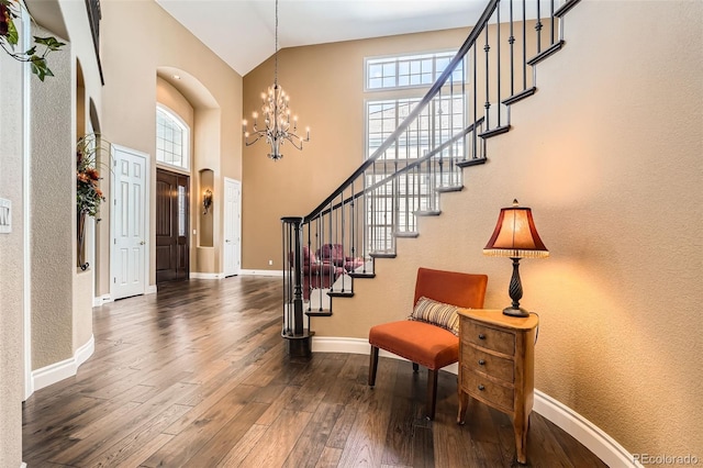 foyer entrance featuring dark wood finished floors, a chandelier, a healthy amount of sunlight, and baseboards