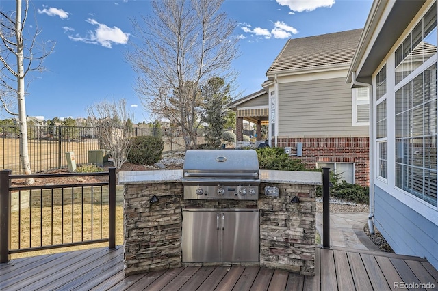 deck with a grill, exterior kitchen, and a fenced backyard