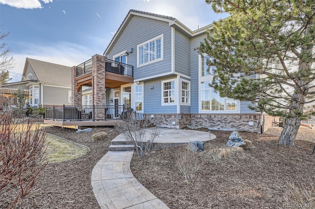 exterior space with brick siding, a balcony, and a patio area