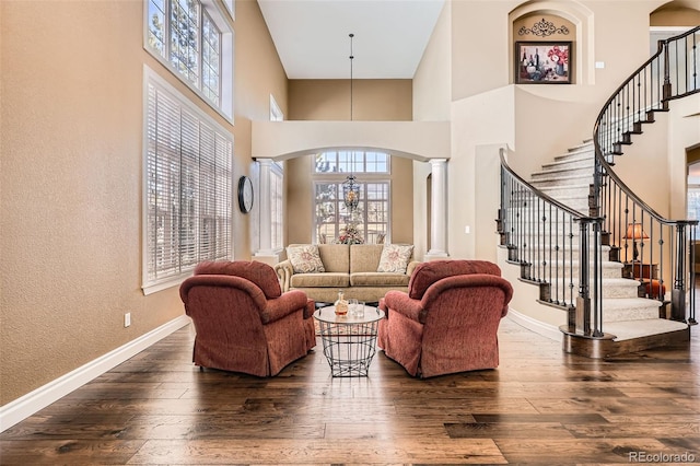 living area featuring baseboards, arched walkways, and dark wood-type flooring