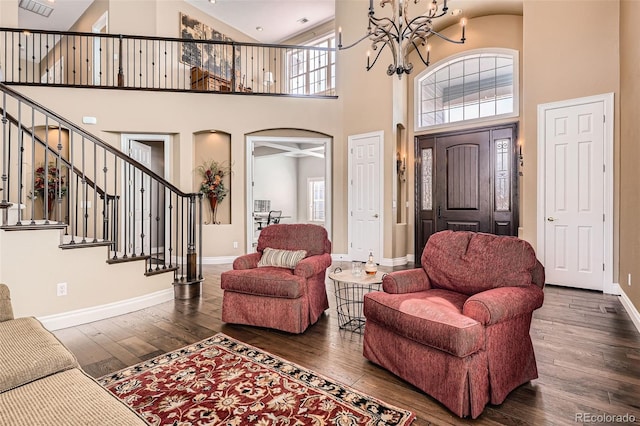 living area with baseboards, arched walkways, stairs, wood-type flooring, and a notable chandelier