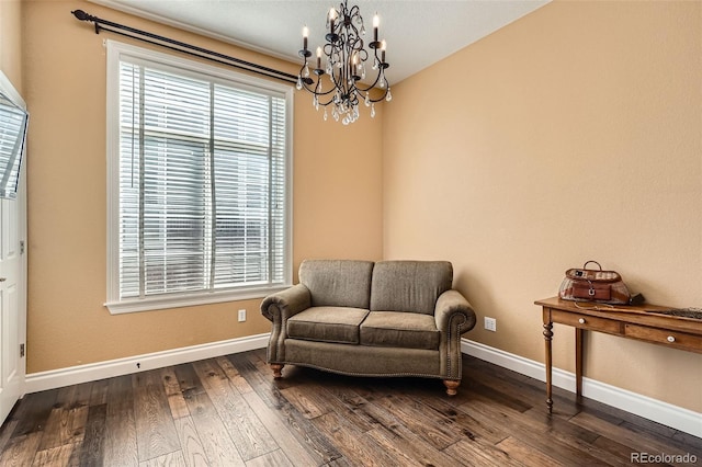 sitting room with a chandelier, baseboards, and dark wood-style flooring