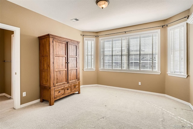 unfurnished bedroom with visible vents, carpet floors, and baseboards