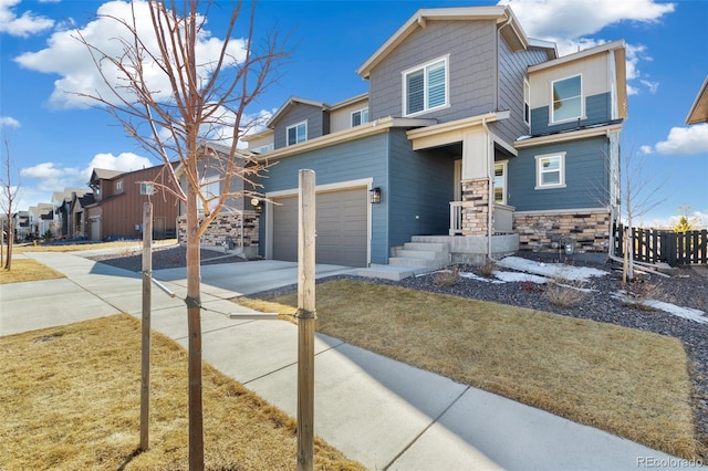 view of front of house featuring stone siding, an attached garage, concrete driveway, and fence