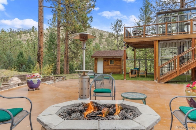 view of patio featuring a wooden deck, an outbuilding, and a fire pit