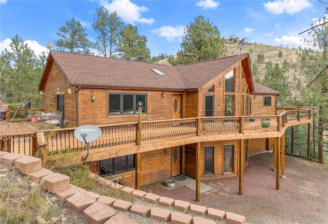 back of house with a shingled roof and a wooden deck