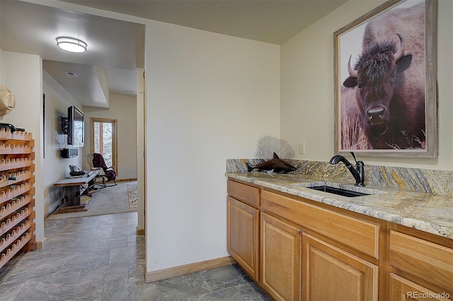 bar with stone finish flooring, visible vents, baseboards, and a sink