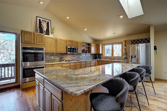 kitchen featuring light wood finished floors, a kitchen island, stainless steel appliances, and open shelves