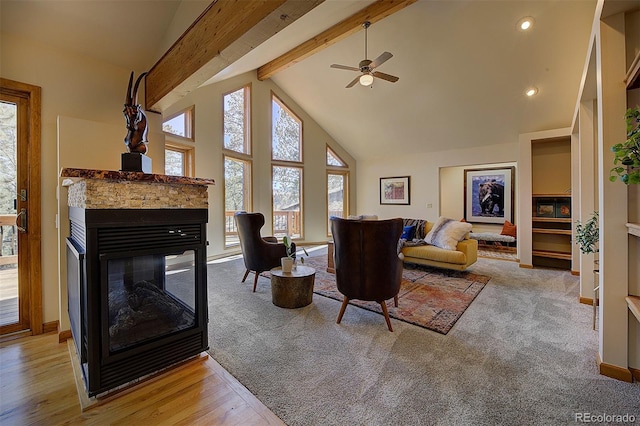 living area featuring a multi sided fireplace, beam ceiling, high vaulted ceiling, and baseboards