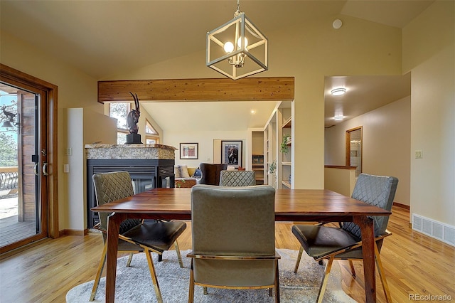 dining room with visible vents, a multi sided fireplace, light wood-style flooring, and vaulted ceiling with beams