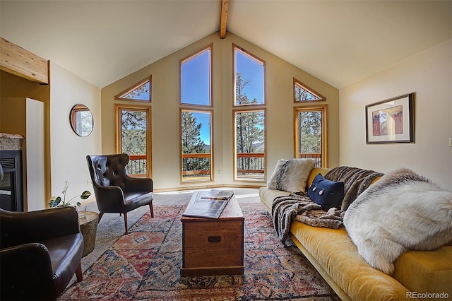 living room with beam ceiling, high vaulted ceiling, and a glass covered fireplace