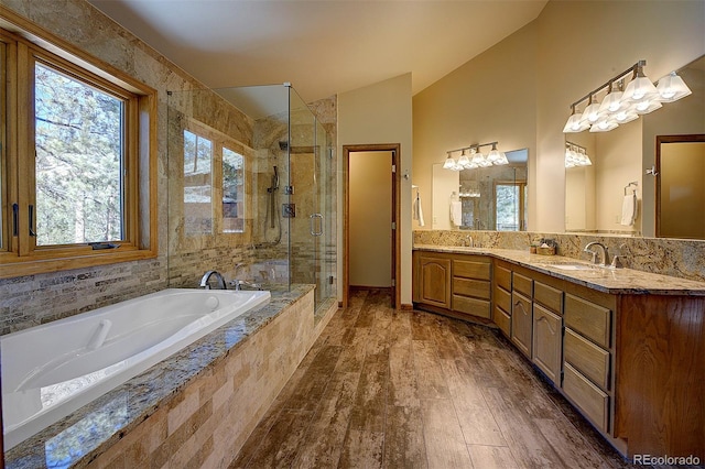 bathroom featuring a garden tub, a sink, wood finished floors, a shower stall, and lofted ceiling