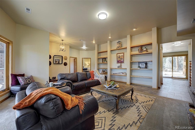 tiled living area featuring built in features, visible vents, baseboards, and a chandelier