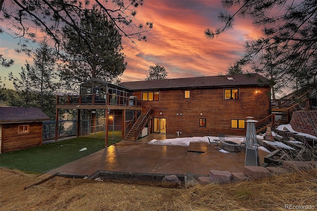 rear view of house with stairway, a yard, a sunroom, an outbuilding, and a patio