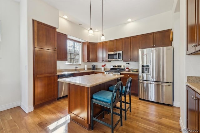 kitchen with a kitchen breakfast bar, appliances with stainless steel finishes, a center island, and light wood-style floors