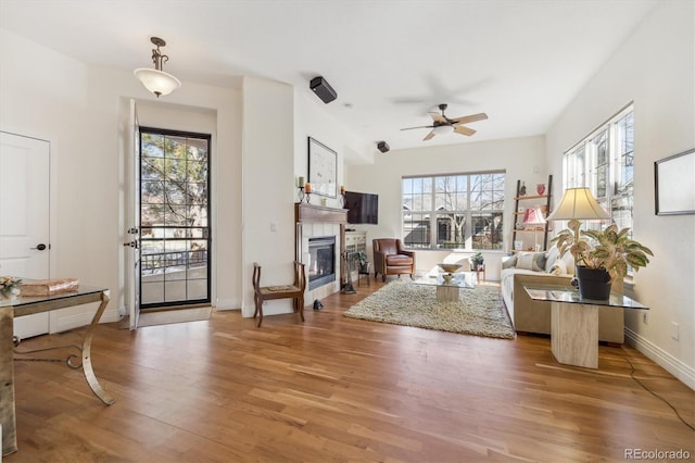 living room with ceiling fan, a healthy amount of sunlight, wood finished floors, and a tile fireplace