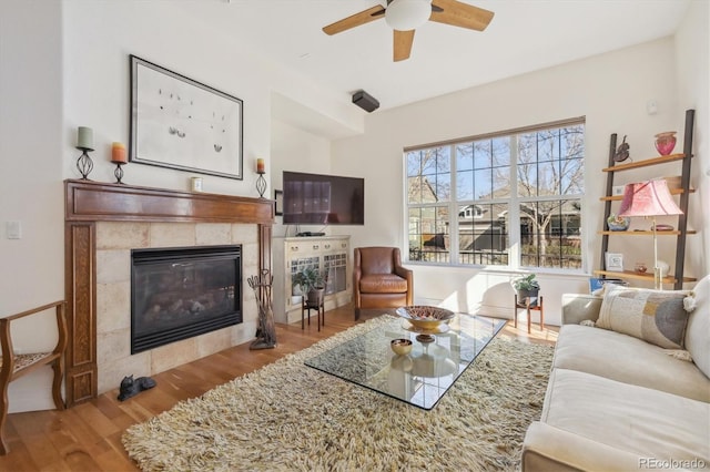 living room with a fireplace, ceiling fan, and wood finished floors