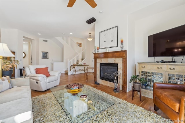 living area featuring visible vents, stairway, ceiling fan, and wood finished floors