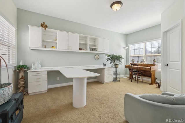 office with built in desk, light colored carpet, and baseboards