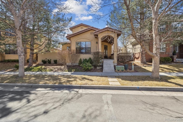 mediterranean / spanish-style home with stucco siding, a tiled roof, and fence