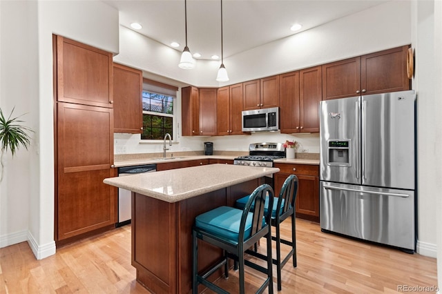 7444 E 9th Ave, Denver, CO 80230 - kitchen with appliances with stainless steel finishes, a sink, light wood-style floors, a center island, and decorative light fixtures