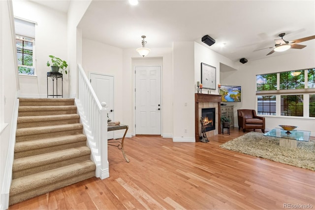 7444 E 9th Ave, Denver, CO 80230 - living area featuring light wood-type flooring, stairway, baseboards, a tiled fireplace, and a ceiling fan