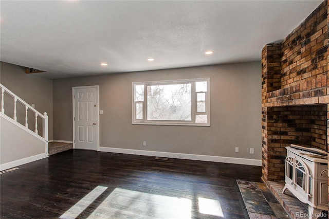 unfurnished living room with dark wood-type flooring and a wood stove