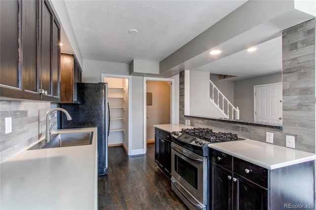 kitchen featuring a textured ceiling, dark hardwood / wood-style flooring, sink, backsplash, and stainless steel range with gas stovetop