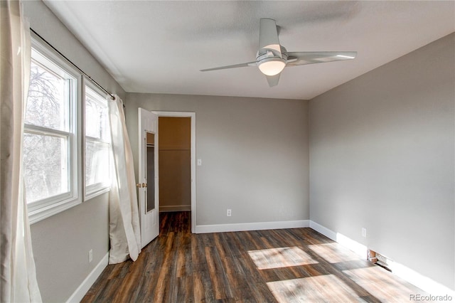 unfurnished bedroom with a spacious closet, a closet, dark hardwood / wood-style flooring, and ceiling fan