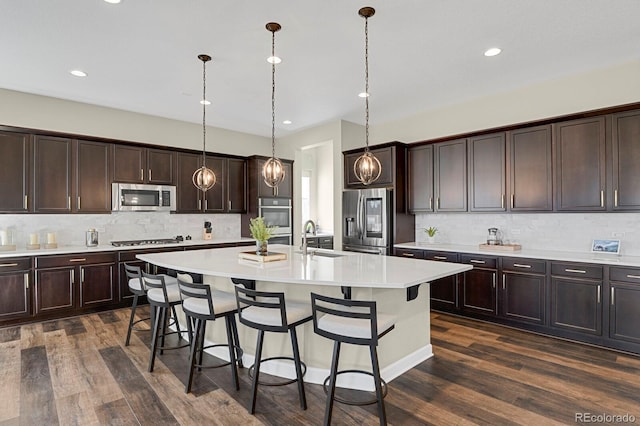 kitchen with a breakfast bar, dark brown cabinets, stainless steel appliances, and a sink