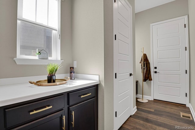 bathroom with visible vents, vanity, baseboards, and wood finished floors