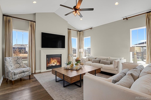 living area featuring dark wood-style floors, a glass covered fireplace, a healthy amount of sunlight, and recessed lighting