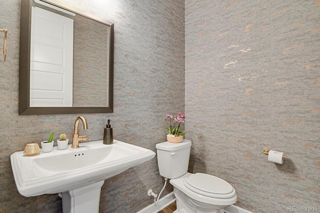 bathroom featuring a sink, toilet, and baseboards